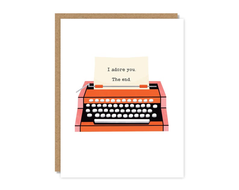 May include: Greeting card featuring a retro orange typewriter with a white keyboard and a sheet of paper. The paper reads "I adore you. The end." The card is set against a white background and framed by a brown border.