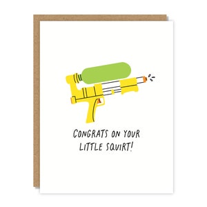 May include: Greeting card with a white background and a cartoon illustration of a yellow water gun with a green water reservoir. The text "Congrats on your little squirt!" is below the water gun. The card has a brown border.