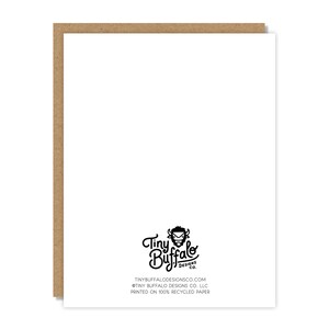 May include: A white greeting card with a brown border. The card features the Tiny Buffalo Designs Co. logo and text at the bottom. The text includes the website address and states the card is printed on 100% recycled paper.