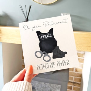 May include: A white card with the text "On your Retirement Detective Pepper" and a black police vest with the word "Police" on it, handcuffs, and a black boot.