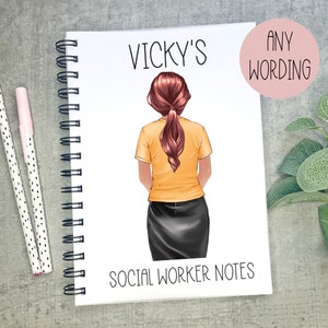 May include: A white spiral bound notebook with a colourful illustration of a woman with red hair wearing a yellow shirt and black skirt. The text "VICKY'S SOCIAL WORKER NOTES" is printed on the front cover. The text "ANY WORDING" is printed on a pink circle sticker.