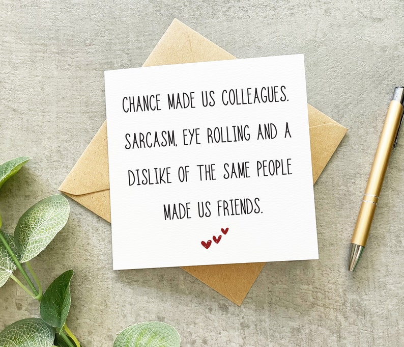 May include: A white card with black text that reads "Chance made us colleagues. Sarcasm, eye rolling and a dislike of the same people made us friends." There are three small red hearts at the bottom of the card.