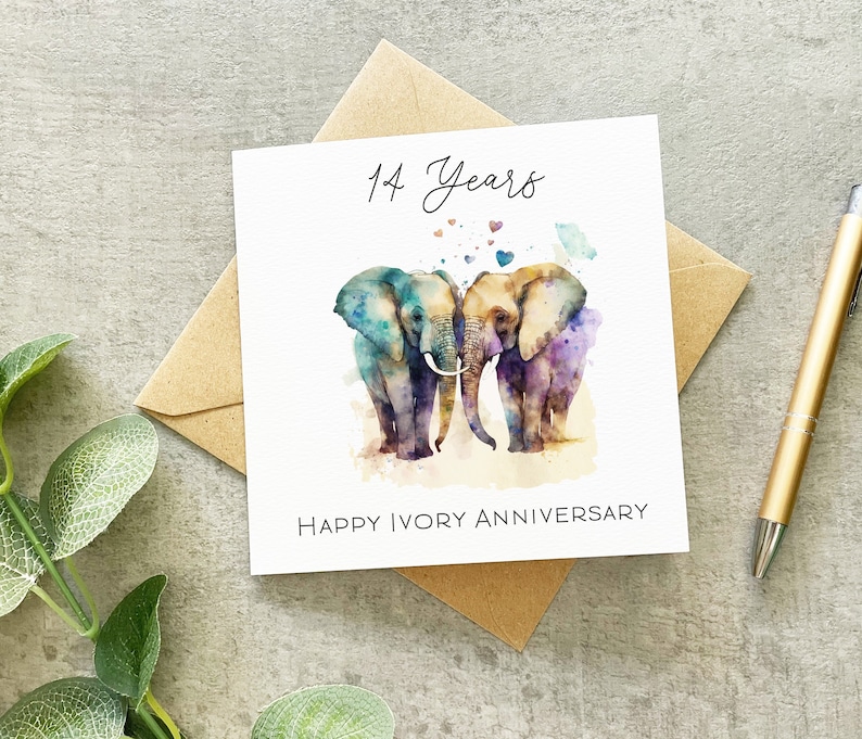 May include: A white card with a watercolor illustration of two elephants standing close together. The elephants are painted in shades of blue, purple, and green. The card says "14 Years" and "Happy Ivory Anniversary".