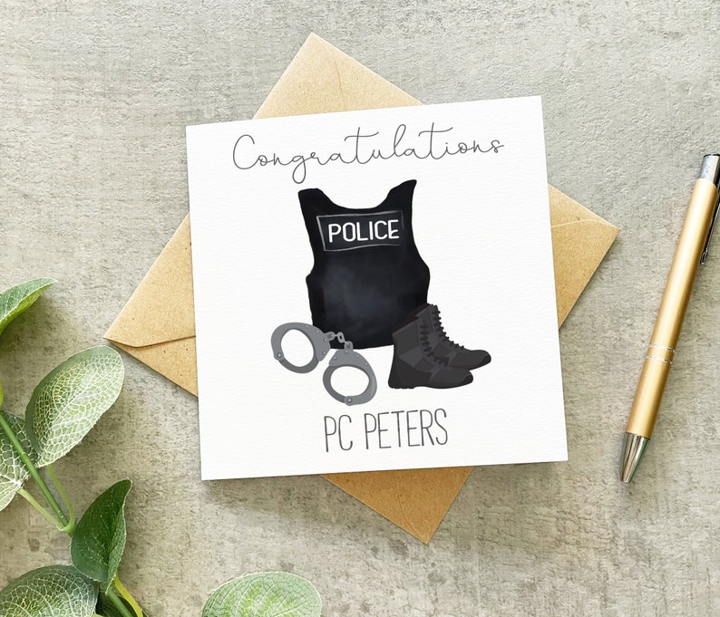 Op de afbeelding: Een witte kaart met de tekst "Congratulations" in zwarte cursieve letters. De kaart toont een zwart politievest met het woord "POLICE" in witte letters, handboeien en zwarte laarzen. De tekst "PC PETERS" staat onder de afbeelding.