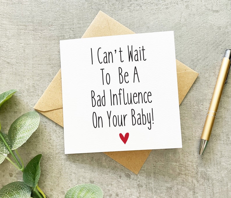 May include: A white card with black text that reads "I Can't Wait To Be A Bad Influence On Your Baby!" with a red heart at the bottom.