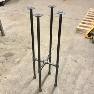May include: Black metal table base with four legs and a cross-shaped support structure.