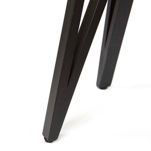 Pode incluir: Close-up das pernas de metal preto de uma mesa ou cadeira. As pernas s&atilde;o anguladas e t&ecirc;m uma forma triangular.