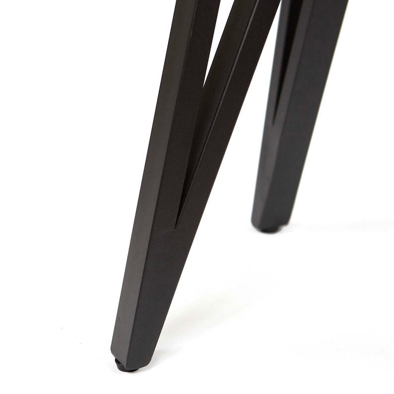 Pode incluir: Close-up das pernas de metal preto de uma mesa ou cadeira. As pernas s&atilde;o anguladas e t&ecirc;m uma forma triangular.