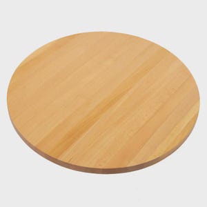 May include: A circular wooden chopping board in a light, natural colour. The board is constructed from parallel strips of wood, giving it a striped appearance. The edges are rounded, and the surface is smooth.