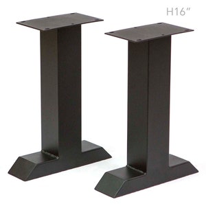 May include: Two black metal table legs, each with a rectangular top plate and a T-shaped base. The legs are 40.6 cm tall. H16"