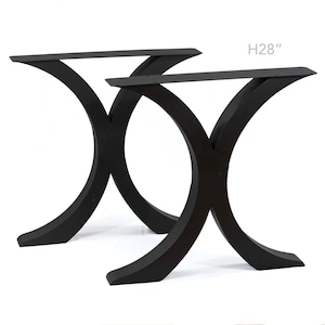 May include: Two black, curved table legs, each 71 cm high. The legs have a modern design, with a wide base that curves inward and then outward to support the tabletop. The legs are made of metal.