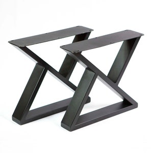 May include: Two black metal table legs with a triangular design. The legs are made of sturdy metal and have a black finish.