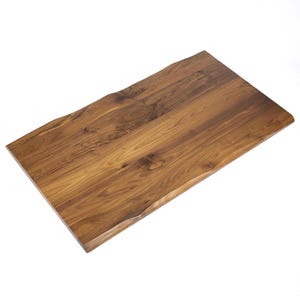 Peut inclure: Une table en bois rectangulaire avec une finition marron chaud naturelle. Les bords ont un design de bord brut, lui donnant un aspect rustique et organique. Le grain du bois est visible, ajoutant à son caractère unique.