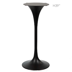 May include: A black metal pedestal table with a round base and a flared stem, supporting a circular top. The table is 39 inches high.