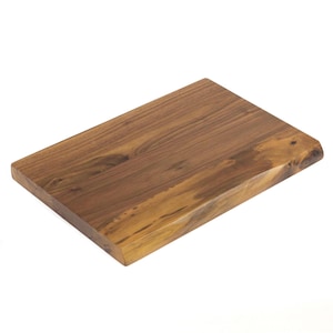 May include: A rectangular wooden chopping board with a natural edge. The board is made of dark brown wood with visible grain patterns. The surface is smooth and appears to be finished with a clear sealant. The chopping board is ideal for food preparation.