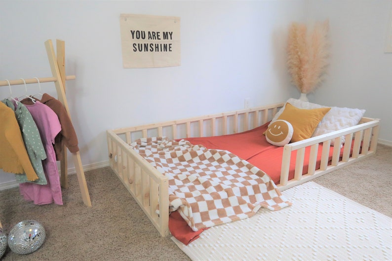 Natural wooden bed frame with 12” high railings. Entry at the side.