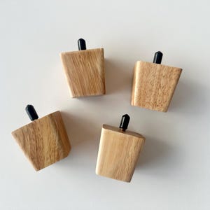 Puede incluir: Cuatro patas de muebles de madera con un acabado de veta de madera natural y detalles negros en la parte superior. Las patas son anguladas y c&oacute;nicas, dise&ntilde;adas para una est&eacute;tica moderna. Probablemente sean para una mesa o silla peque&ntilde;a.