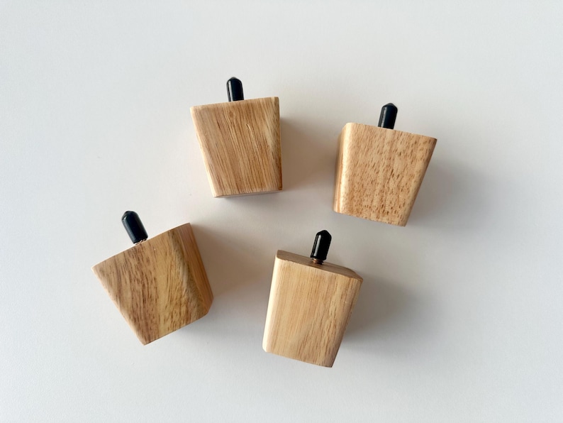 Puede incluir: Cuatro patas de muebles de madera con un acabado de veta de madera natural y detalles negros en la parte superior. Las patas son anguladas y c&oacute;nicas, dise&ntilde;adas para una est&eacute;tica moderna. Probablemente sean para una mesa o silla peque&ntilde;a.