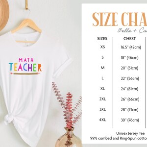 K&ouml;nnte beinhalten: Wei&szlig;es T-Shirt mit dem Text "MATH TEACHER" in Regenbogenfarben und einer braunen Bleistiftgrafik. Gr&ouml;&szlig;entabelle f&uuml;r das Unisex-Jersey-T-Shirt Bella + Canvas 3001, mit Brust- und L&auml;ngenma&szlig;en in Zoll und Zentimetern f&uuml;r die Gr&ouml;&szlig;en XS bis 4XL.