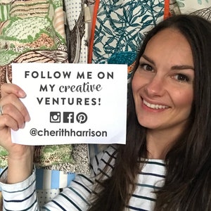 Puede incluir: Una mujer sosteniendo una tarjeta blanca con el texto "FOLLOW ME ON MY CREATIVE VENTURES! @cheriththarrison" y los iconos de redes sociales para Instagram, Facebook y Pinterest. Lleva una camisa a rayas y tiene el pelo largo y casta&ntilde;o.