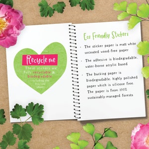 May include: A close-up of a notebook page with the text "Recycle me" written in pink on a green heart-shaped sticker. The text "These stickers are fully recyclable & biodegradable (including the backing sheet)" is written below the sticker. The page also includes the text "Eco Friendly Stickers" and a list of details about the paper and adhesive used in the stickers.