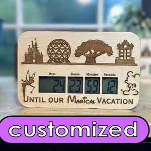 May include: A wooden countdown clock with a digital display showing 24 days, 23 hours, 59 minutes, and 12 seconds. The clock is decorated with laser-engraved images of Disney World landmarks, including Cinderella's Castle, Spaceship Earth, the Tree of Life, and the Tower of Terror. The text "Until our Magical Vacation" is also engraved on the clock.