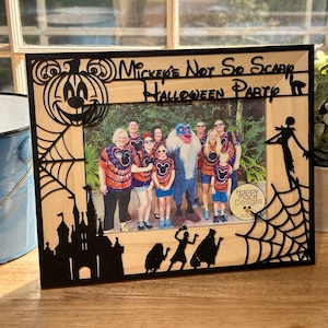 May include: A wooden picture frame with a black silhouette of Mickey Mouse's head and a pumpkin. The frame says "Mickey's Not So Scary Halloween Party". The frame has a spiderweb design and a photo of a family in front of a large, furry, blue monster.