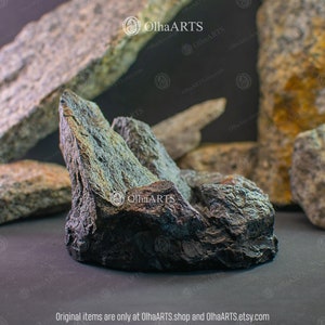May include: A dark gray, rough-textured rock formation with sharp edges. The rock is shaped like a mountain range and has a natural, organic look.