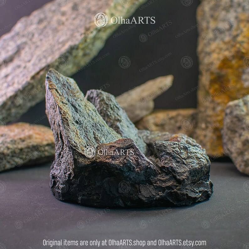May include: A dark gray, rough-textured rock formation with sharp edges. The rock is shaped like a mountain range and has a natural, organic look.