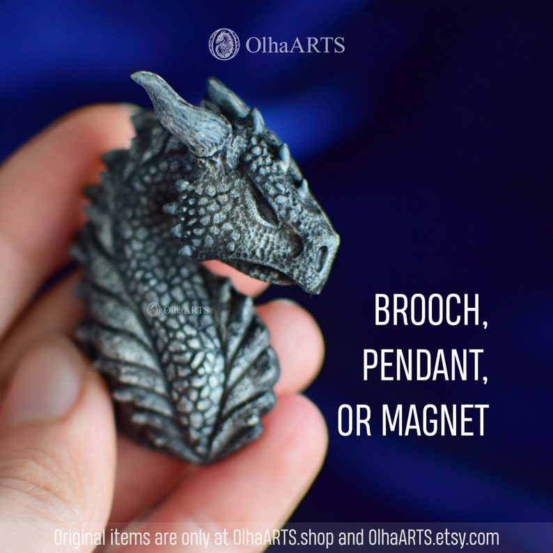 May include: A small, detailed, gray dragon head sculpture. The dragon has a textured, scaly body and a fierce expression. It can be used as a brooch, pendant, or magnet.