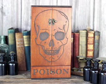 Skull engraved wooden apothecary cabinet with skull engraving and poison drawer holds six brown medicine bottles with glass stoppers