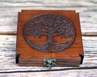 May include: A wooden box with a dark brown finish and a laser-cut tree of life design on the lid. The box has a square shape with a metal clasp closure, showcasing a rustic aesthetic.