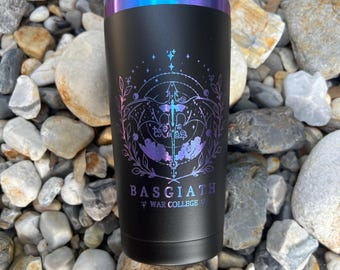 May include: A matte black stainless steel tumbler with a clear lid and a metallic blue-to-purple gradient rim. The front features a holographic dragon graphic surrounded by celestial and floral line art, with the text BASGIATH WAR COLLEGE.