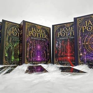 Puede incluir: Una colección de cinco libros de tapa dura titulados James Potter de G. Norman Lippert. Cada libro presenta bordes dorados ornamentados y portadas vibrantes en azul, verde, morado, rojo y dorado, con los títulos claramente impresos al frente.