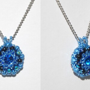 以下が含まれることがあります： 銀色のチェーンネックレスに、青と黒のビーズでできたペンダントが飾られています。ペンダントの中央には、大きな青いクリスタルが輝いています。