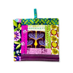 May include: A colorful patchwork pot holder with a green, pink, purple, and yellow design. The pot holder has a loop for hanging.