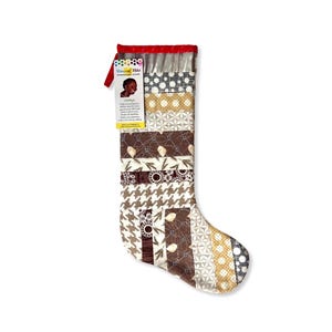 May include: A patchwork Christmas stocking with a variety of patterns in brown, tan, and white. The stocking has a red top and a tag with text and a picture of a child. The patterns include houndstooth, floral, and geometric designs.