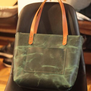 The tote bag's adjustable and detachable leather strap for shoulder or crossbody wear