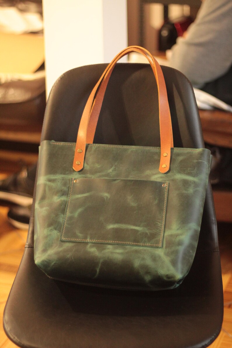 The tote bag's adjustable and detachable leather strap for shoulder or crossbody wear