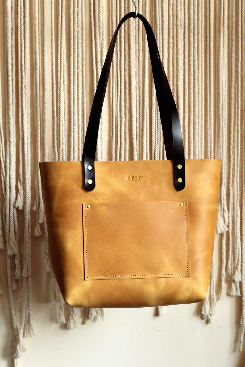 Customizable leather tote in three neutral colors: camel, chocolate, and slate grey