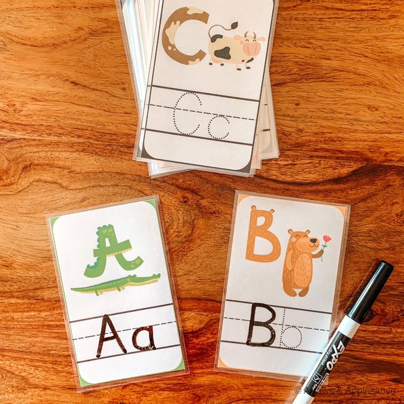 Puede incluir: Un conjunto de tarjetas de aprendizaje del alfabeto con un animal diferente en cada tarjeta. Las tarjetas son transparentes y tienen un marcador negro en el lateral. Las tarjetas presentan las letras A, B y C con un cocodrilo, un oso y una vaca, respectivamente.