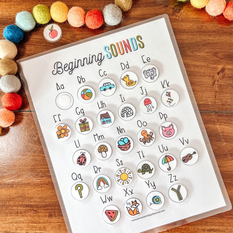 May include: A white sheet of paper with the words "Beginning Sounds" printed in colorful letters. The paper is divided into a grid with 26 circles, each containing a letter of the alphabet and a corresponding image. The images are colorful and whimsical, such as a duck, a house, and a ladybug.