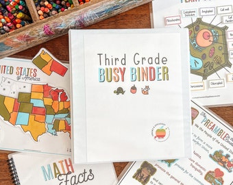 Könnte beinhalten: Ein weißer Ordner mit dem Text "Third Grade Busy Binder" in bunten Buchstaben. Der Ordner ist geöffnet und zeigt eine Seite mit einem Diagramm einer Pflanzenzelle und eine Seite mit einer Karte der USA.