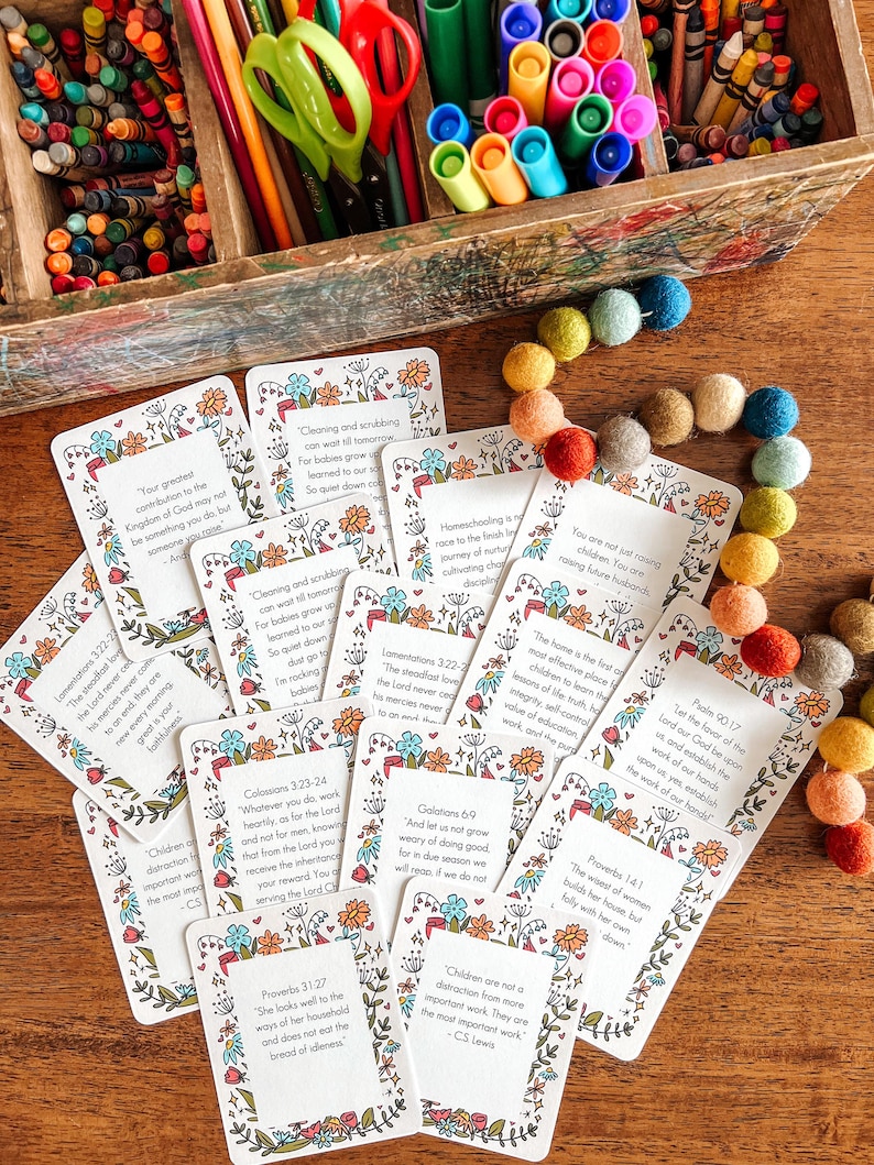 May include: A set of colorful cards with inspirational quotes and bible verses. The cards feature floral illustrations and are arranged on a wooden surface.