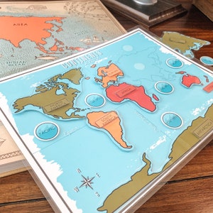 May include: A blue and green world map puzzle with continents and oceans labeled. The continents are color-coded and the oceans are represented by blue circles.