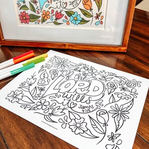 May include: A framed floral art print with colorful flowers and the text "James 4:15". A black and white coloring page with the words "If the Lord wills it" and floral designs is in the foreground. Four colored markers are on the left.