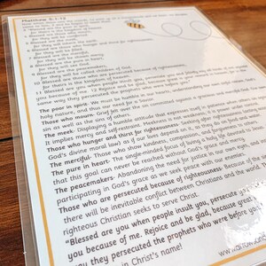 May include: A yellow and black bee illustration with a speech bubble containing the text "Matthew 5:1-12". The text below the bee is a list of verses from the Bible, including "Blessed are the poor in spirit", "Blessed are those who mourn", "Blessed are the meek", "Blessed are those who hunger and thirst for righteousness", "Blessed are the merciful", "Blessed are the pure in heart", "Blessed are the peacemakers", and "Blessed are those who are persecuted because of righteousness".