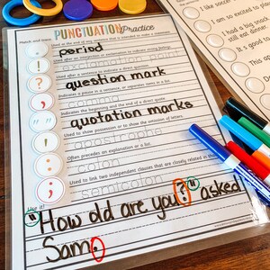May include: A colorful educational chart with punctuation marks and their definitions. The chart includes a period, exclamation point, question mark, comma, quotation marks, apostrophe, colon, and semicolon. The chart also includes a sentence with a question mark and the word "asked" written in black marker.