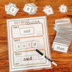 May include: A colorful educational game for kids featuring the word "said" in a sight word builder activity. The game includes letter tiles, a dry-erase marker, and a worksheet with instructions to read, build, and write the word.