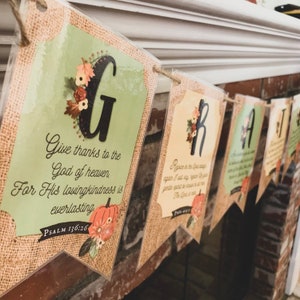 May include: A Thanksgiving banner with a burlap background and fall-themed decorations. The banner features the word "GRATEFUL" with each letter on a separate flag. Each flag has a different Bible verse about gratitude.